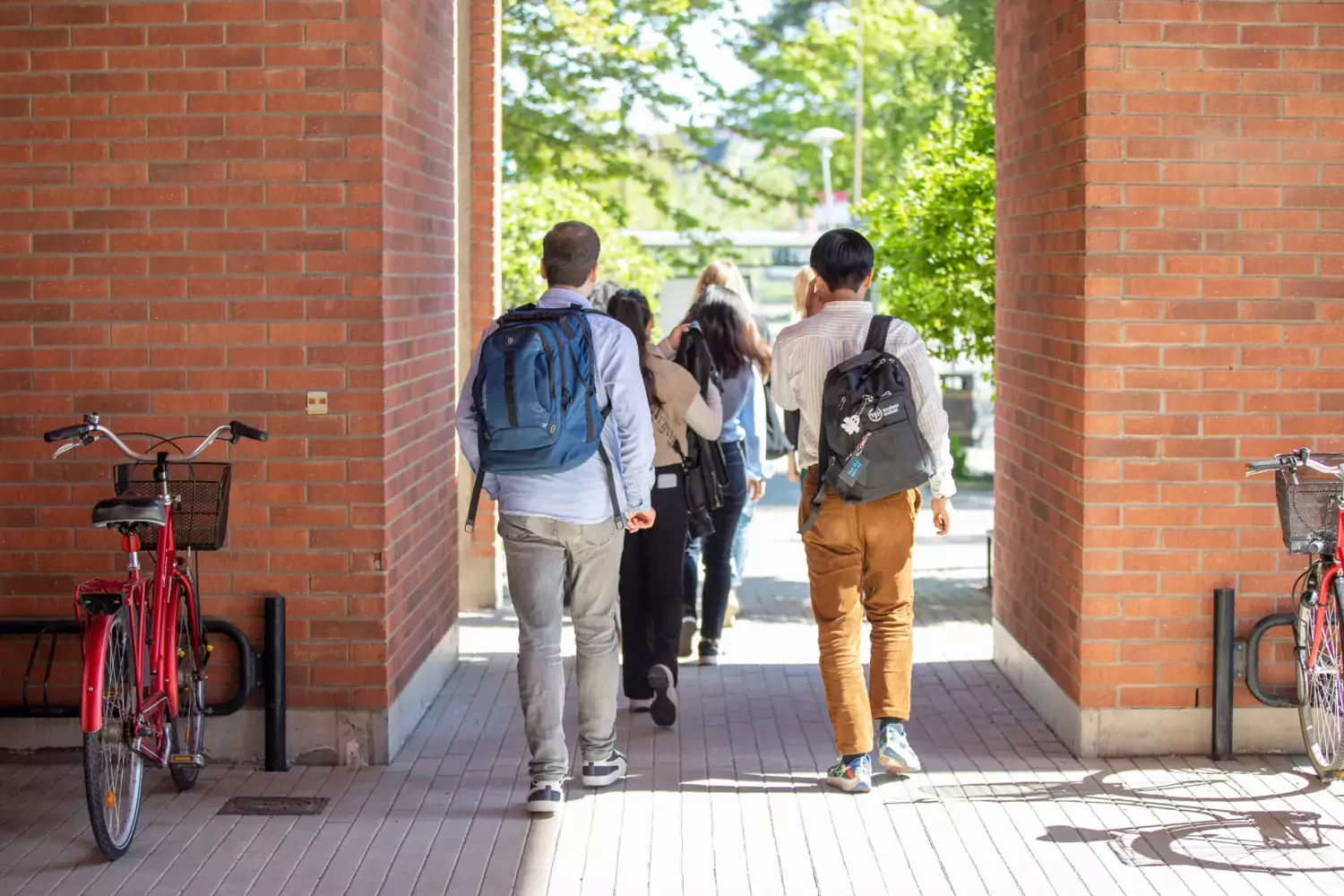 Studenter i grupp går på campus med KI ryggsäck.