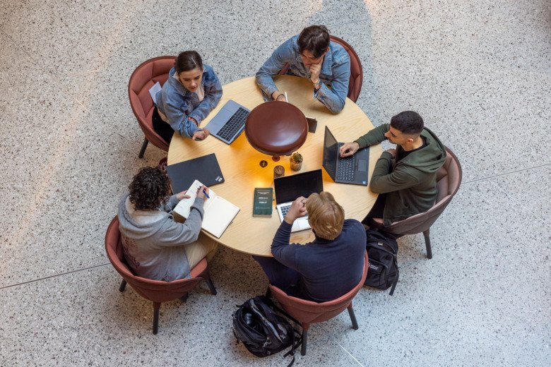 Studenter sitter runt ett bord med sina laptops och pluggar