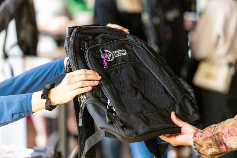 En person ger en student sin KI-ryggsäck.