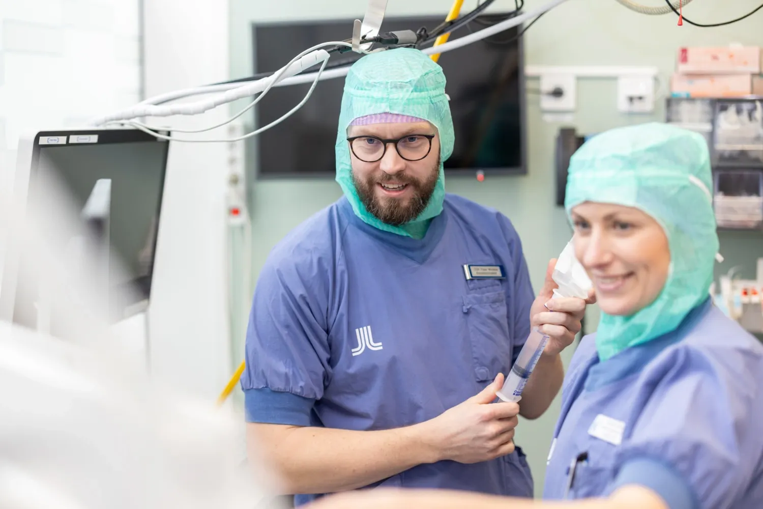 En man och en kvinna, sjuksköterskor, i operationskläder tittar mot kameran.