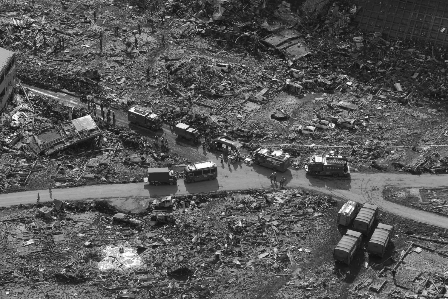 View over a disaster scene with destroyed houses and rescue vehicles following an earth quake