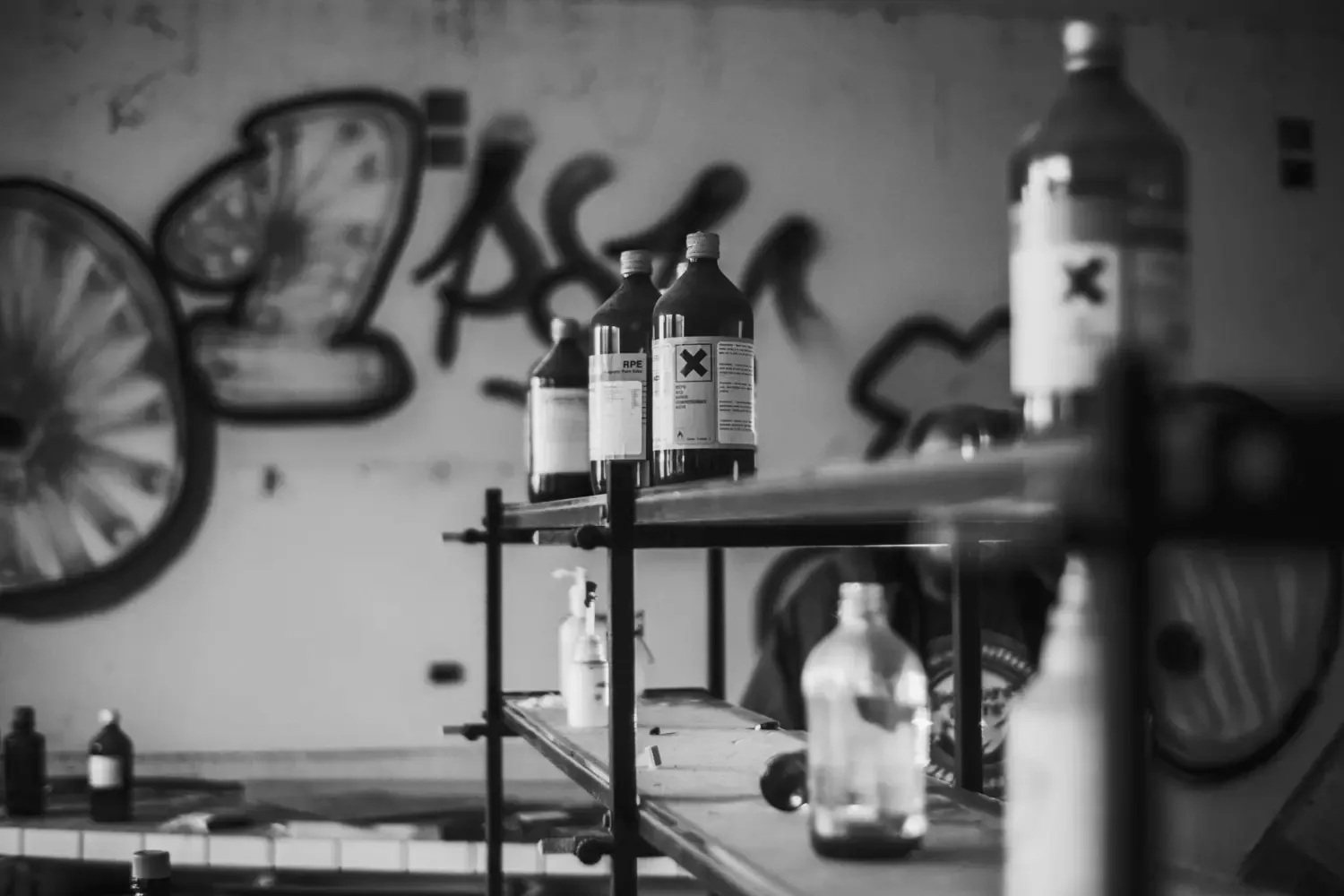 Fotografi på bruna glasflaskor på ett bord i ett garage med farlig kemikalier ettiketer på.