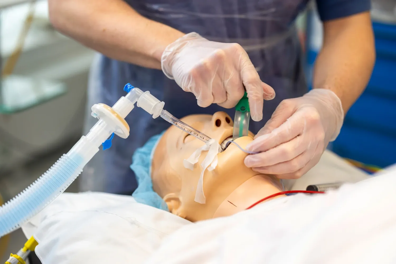 En specialistsjuksköterskestudent inom anestesivård för in en tub i svalget på en docka.
