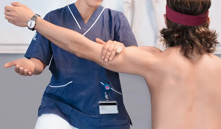En fysioterapeutstudent undersöker en patients arm.