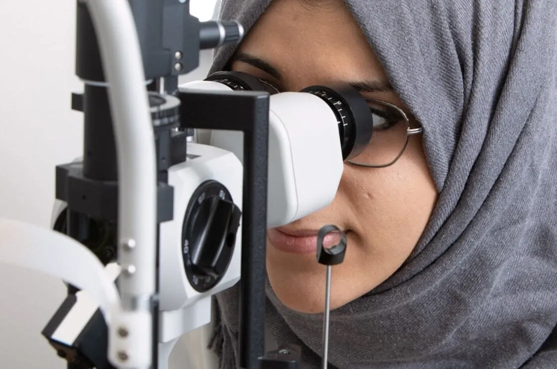 En student på optikerprogrammet tillika digital ambassadör på KI tittar i en autorefraktor.