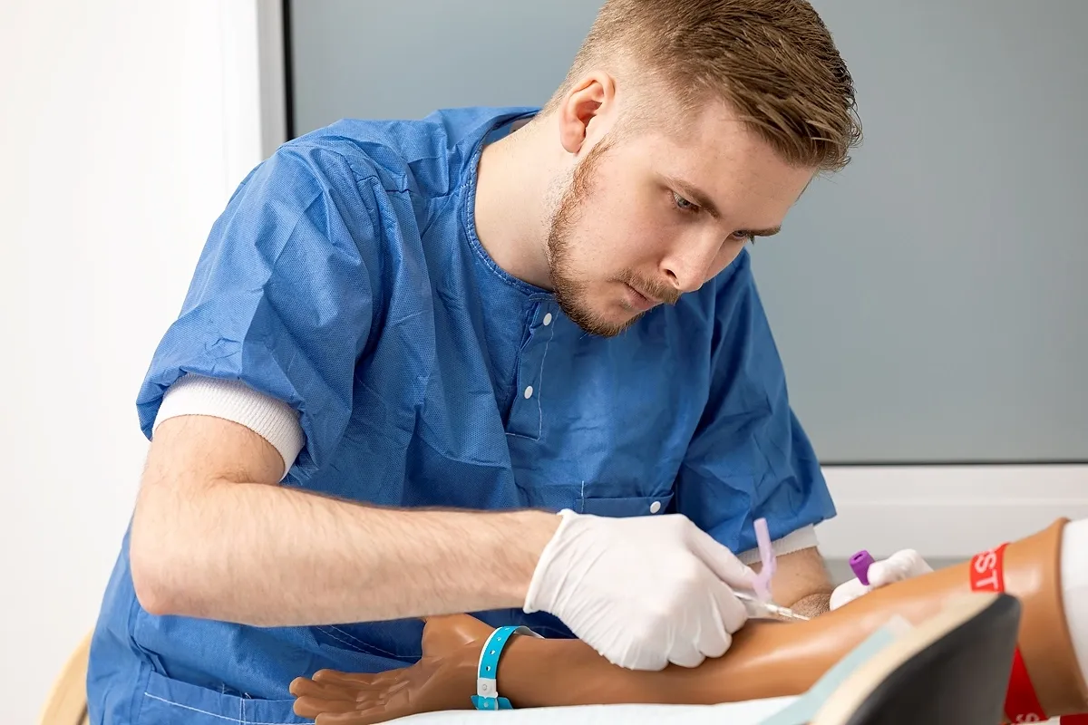 En sjuksköterskestudent utför en simulerad injektion på en docka.