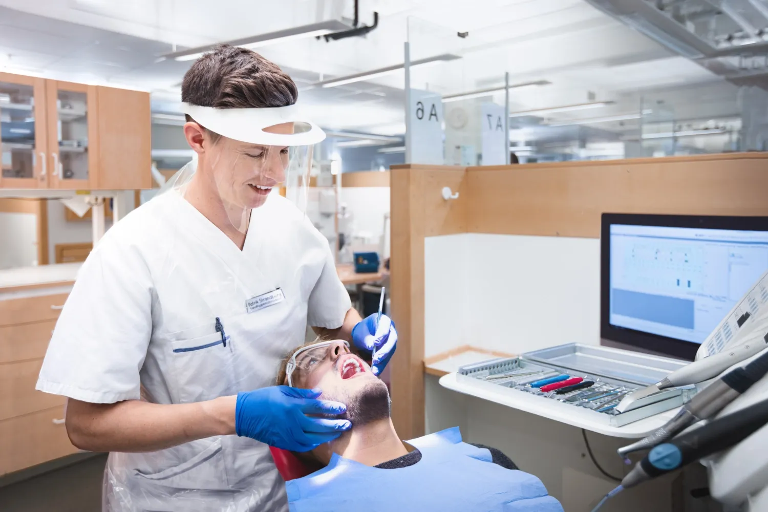 En tandhygieniststudent undersöker en klasskamrats munhåla.