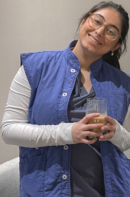 Röntgensjuksköterskestudent i blå och vita arbetskläder tittar in i kameran